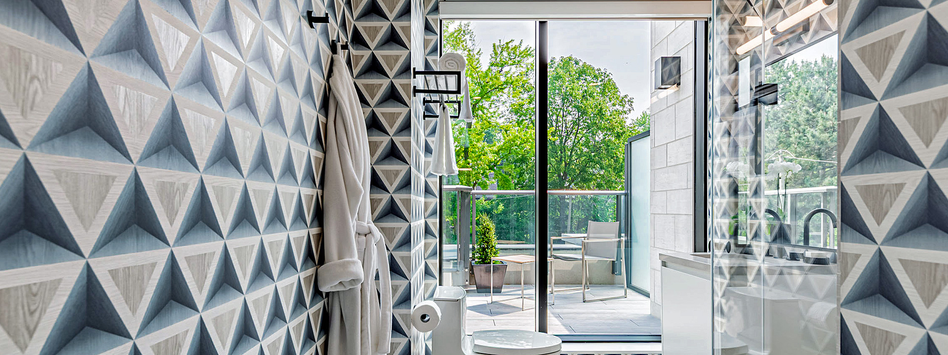 Geo Glam Bath: a Toronto bathroom wrapped in 3D triangle wallpaper, with a glass shower and a view to the terrace
