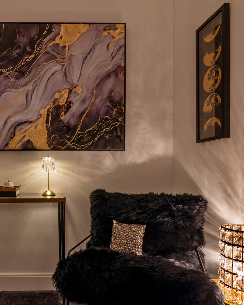 Lounge corner with gold-veined artwork, a brass table lamp and a shaggy armless chair