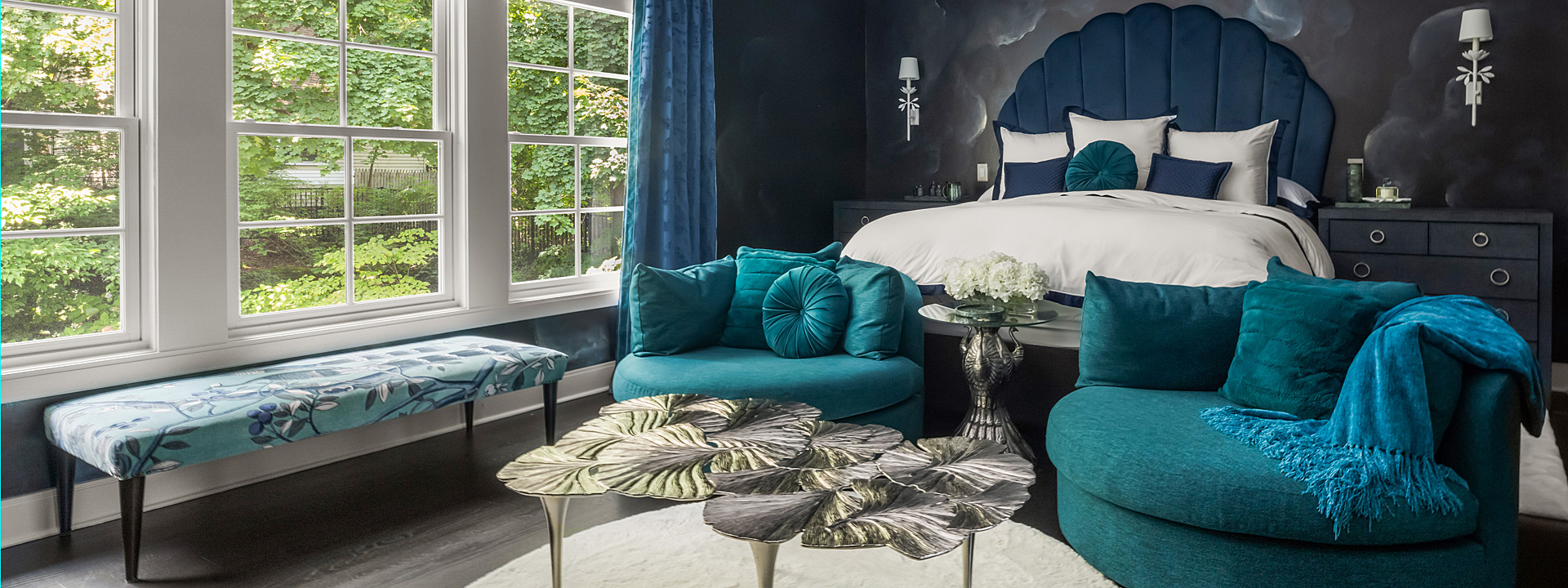 Midnight Garden Suite: a primary bedroom with metallic cloud wallpaper, a scalloped velvet headboard and teal swivel chairs