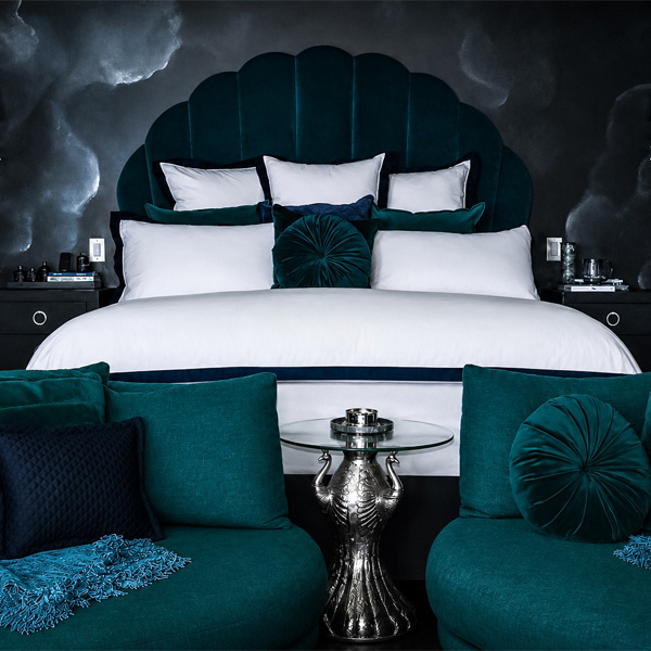 Midnight Garden Suite: a scalloped velvet headboard between teal swivel chairs and a silver peacock side table